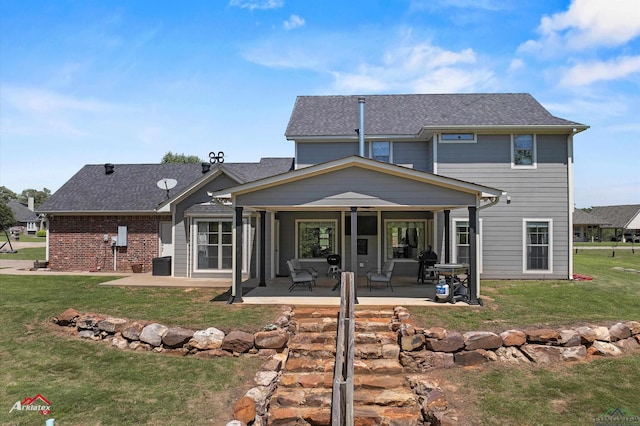 rear view of house with a patio area, a shingled roof, and a lawn