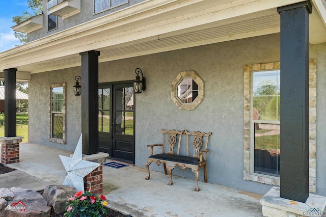 entrance to property with covered porch and stucco siding