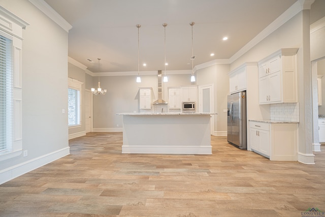 kitchen with appliances with stainless steel finishes, white cabinets, wall chimney range hood, and decorative backsplash