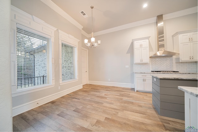 kitchen featuring white cabinets, wall chimney exhaust hood, ornamental molding, and tasteful backsplash