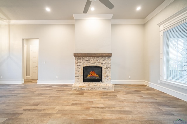 unfurnished living room featuring a ceiling fan, baseboards, light wood-style floors, a brick fireplace, and crown molding