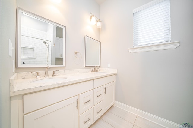 full bath featuring walk in shower, a sink, baseboards, and double vanity