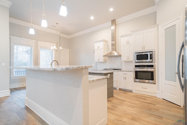 kitchen featuring stainless steel appliances, backsplash, light wood-style flooring, wall chimney range hood, and an island with sink