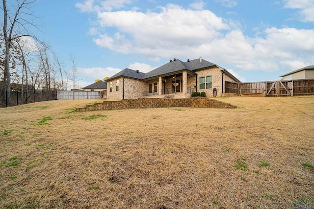 back of house with a patio, brick siding, a lawn, and fence