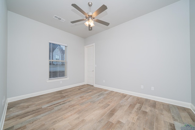 spare room featuring a ceiling fan, light wood-type flooring, visible vents, and baseboards