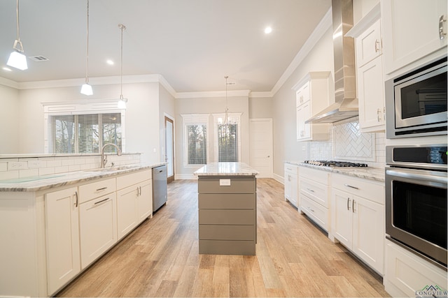 kitchen featuring visible vents, a center island, stainless steel appliances, crown molding, and wall chimney range hood