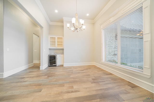 unfurnished living room with light wood-type flooring, beverage cooler, baseboards, and crown molding