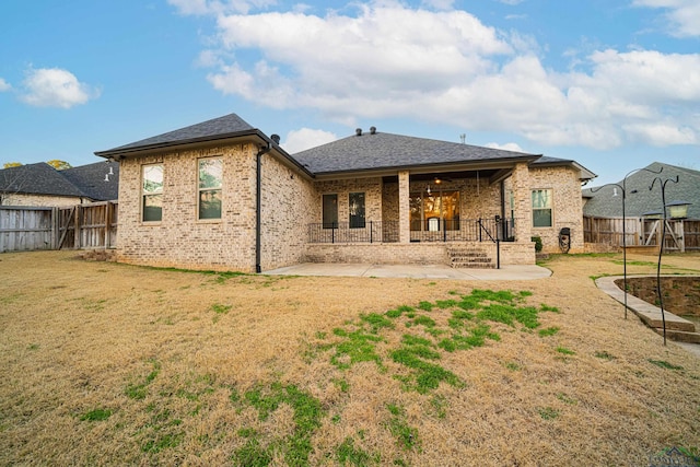 rear view of house featuring a patio, a yard, a fenced backyard, and brick siding