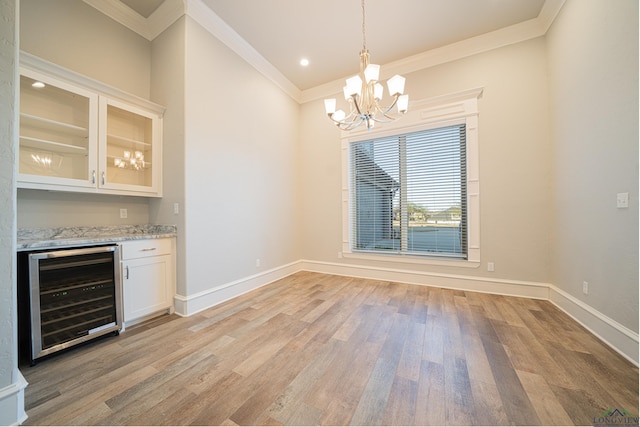 unfurnished dining area featuring ornamental molding, beverage cooler, light wood-style flooring, and baseboards