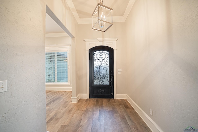 entrance foyer featuring ornamental molding, a textured wall, and wood finished floors