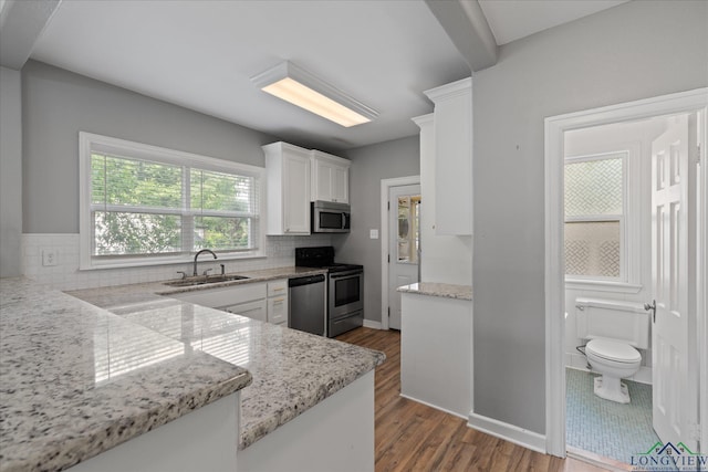 513 E Young, Longview, TX 75602 - kitchen featuring appliances with stainless steel finishes, a sink, white cabinets, wood finished floors, and backsplash
