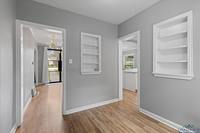 513 E Young, Longview, TX 75602 - corridor featuring built in shelves, wood finished floors, baseboards, a chandelier, and plenty of natural light