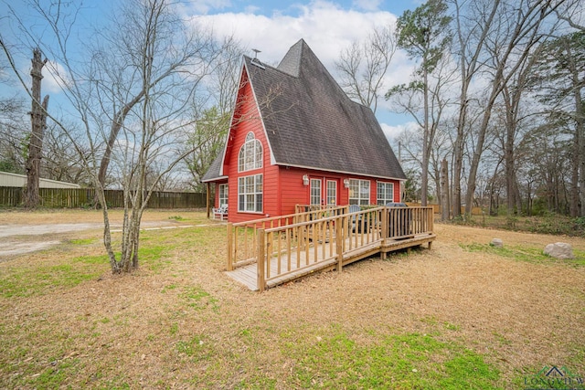 view of property exterior featuring a shingled roof, a lawn, and a wooden deck