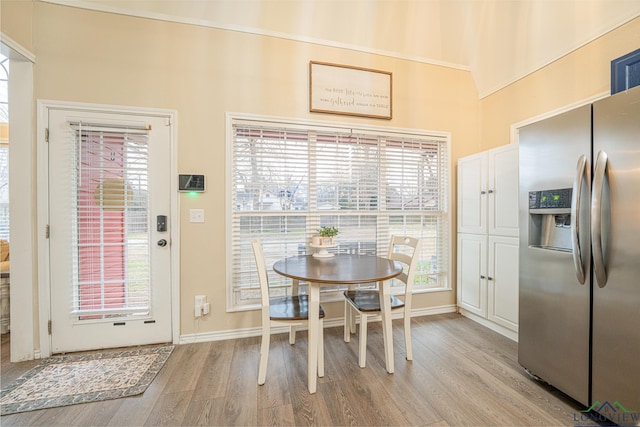 dining space featuring light wood-type flooring, a healthy amount of sunlight, and baseboards