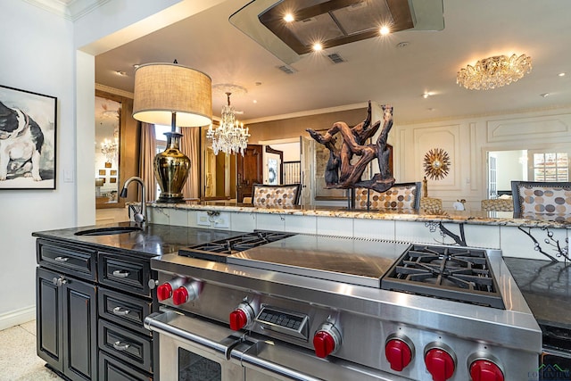 kitchen featuring pendant lighting, high end stainless steel range oven, ornamental molding, a sink, and dark cabinets