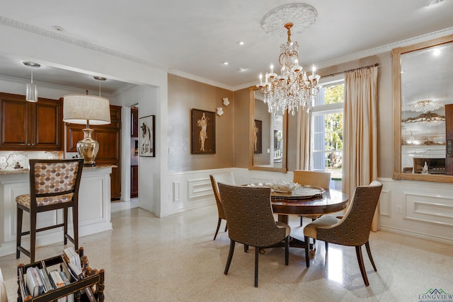 dining space with light speckled floor, a decorative wall, ornamental molding, wainscoting, and an inviting chandelier