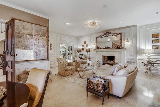 living area with light speckled floor, crown molding, a decorative wall, and a lit fireplace