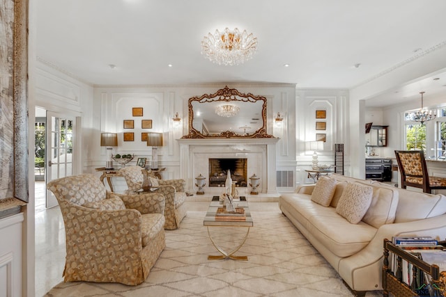 living area featuring crown molding, a notable chandelier, a decorative wall, a high end fireplace, and plenty of natural light