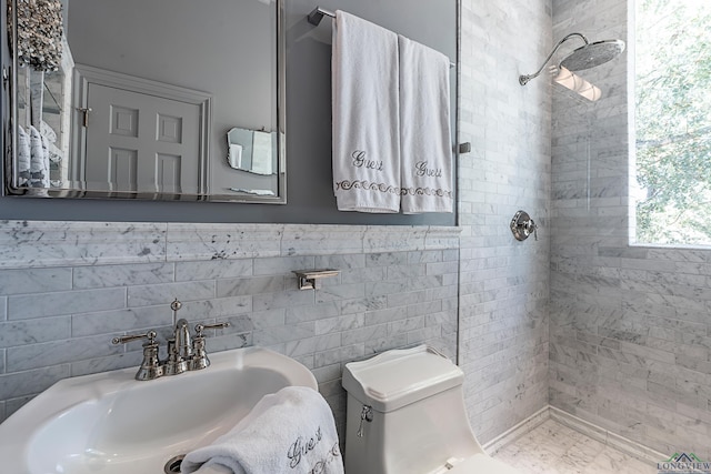 bathroom featuring tile walls, a sink, a shower stall, and toilet