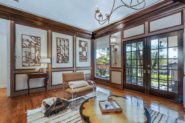 living area featuring ornamental molding, french doors, wood finished floors, and a decorative wall