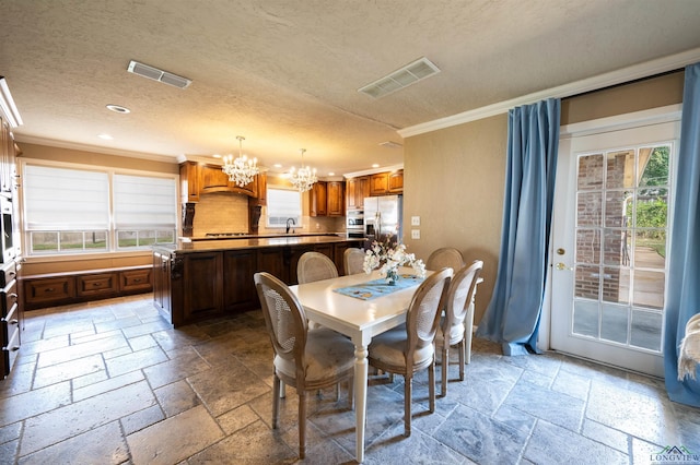 dining area featuring crown molding, sink, a textured ceiling, and a notable chandelier