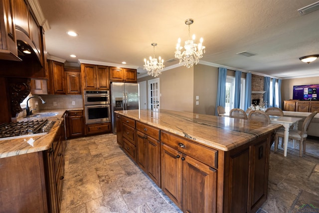 kitchen featuring stainless steel appliances, sink, decorative light fixtures, a chandelier, and a center island