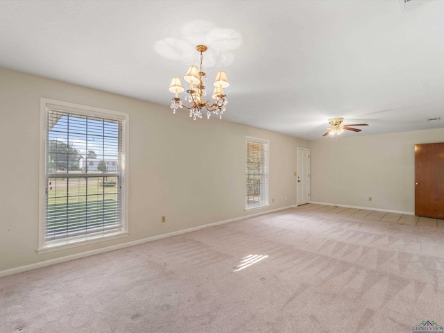 carpeted spare room with ceiling fan with notable chandelier