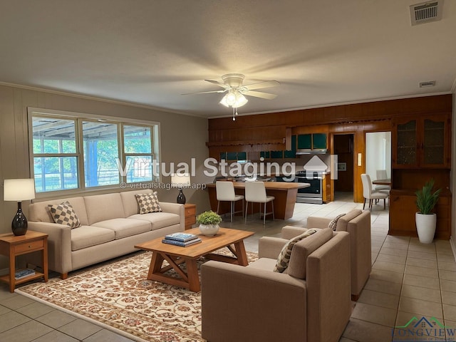 tiled living room featuring ceiling fan, crown molding, and wood walls