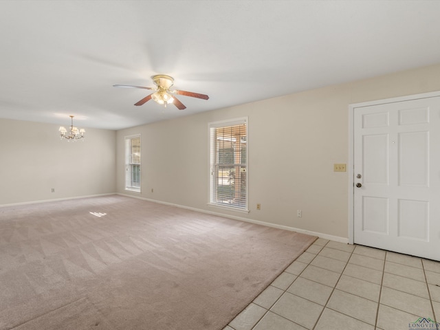 carpeted spare room with ceiling fan with notable chandelier