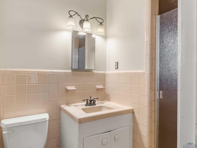 bathroom featuring vanity, toilet, and tile walls