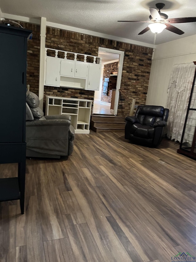 living room with dark hardwood / wood-style floors, a textured ceiling, and brick wall