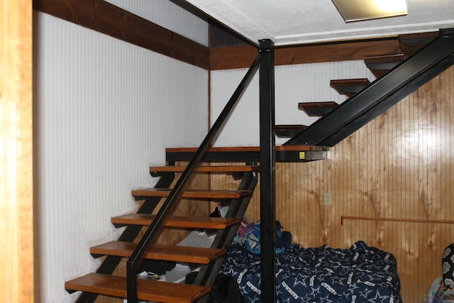 stairway featuring wooden walls