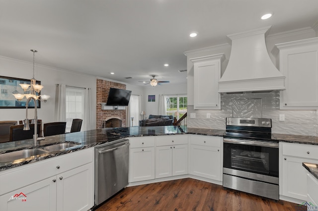 kitchen with sink, a brick fireplace, white cabinets, custom range hood, and appliances with stainless steel finishes