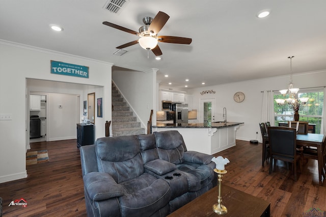 living room with ceiling fan with notable chandelier, dark hardwood / wood-style flooring, crown molding, and sink