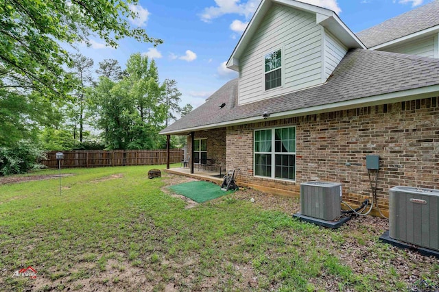 rear view of house with a patio area, central air condition unit, and a yard