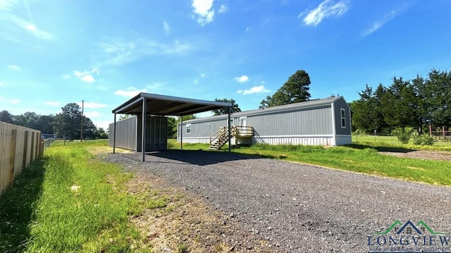 exterior space featuring a carport, gravel driveway, and fence