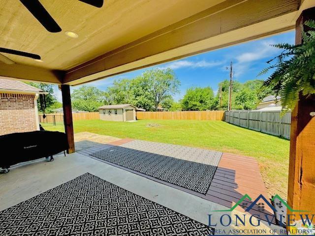 view of patio / terrace featuring an outbuilding, ceiling fan, a fenced backyard, and a storage unit