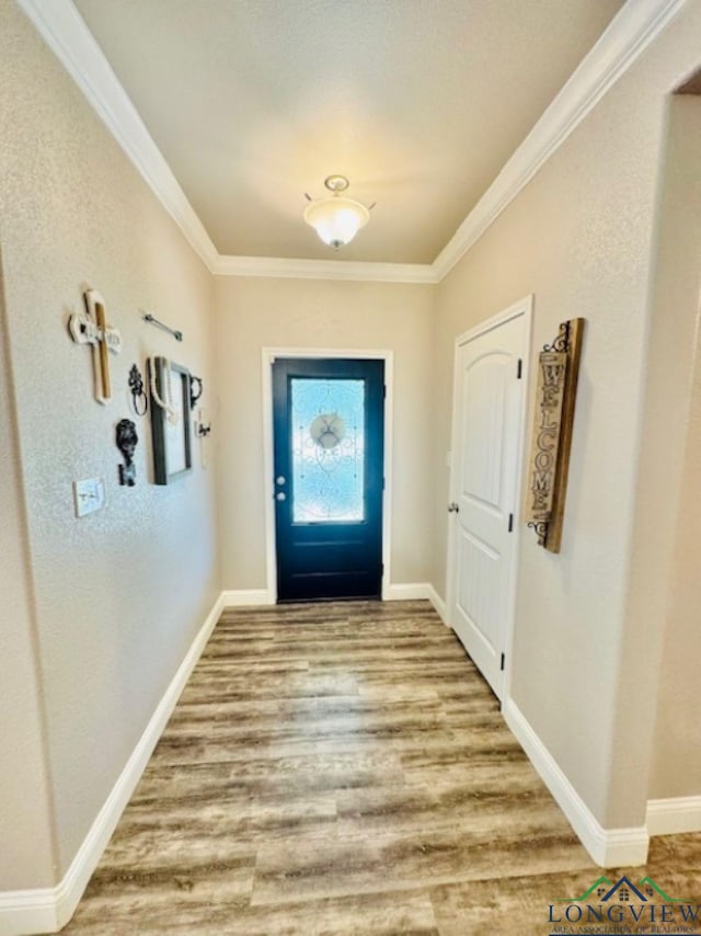 doorway to outside with baseboards, crown molding, and wood finished floors