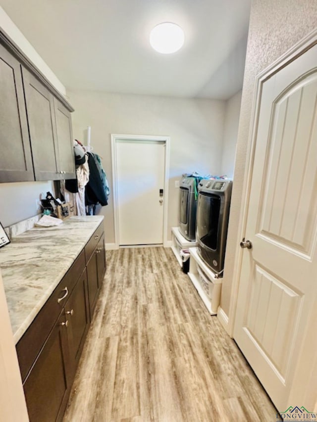 laundry area featuring light wood finished floors, cabinet space, and independent washer and dryer