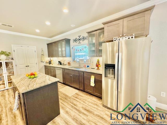 kitchen featuring dishwasher, ornamental molding, visible vents, a sink, and stainless steel fridge with ice dispenser