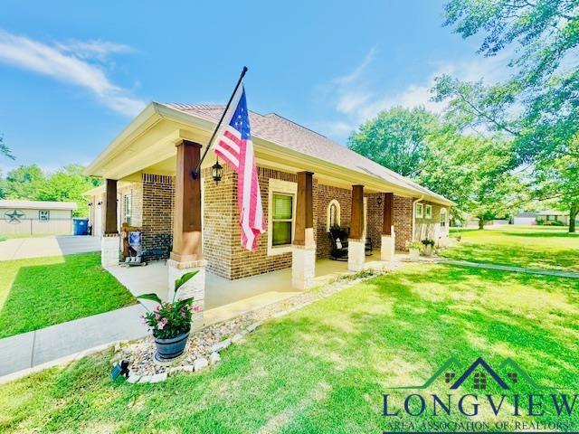exterior space with covered porch, brick siding, and a front yard