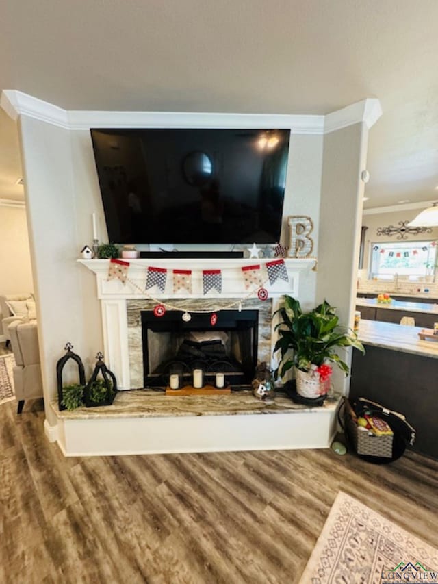 living area featuring ornamental molding, a tile fireplace, and wood finished floors