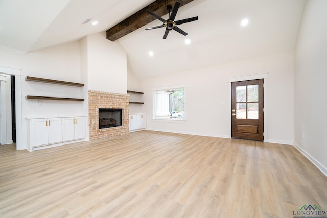 unfurnished living room featuring a fireplace, lofted ceiling with beams, light hardwood / wood-style floors, and ceiling fan