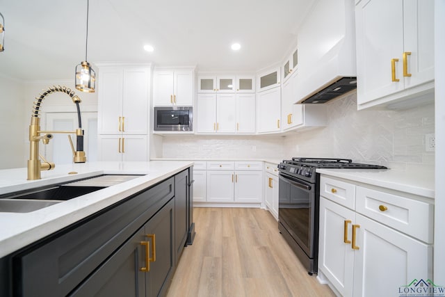 kitchen featuring sink, premium range hood, stainless steel microwave, white cabinets, and black range with gas stovetop