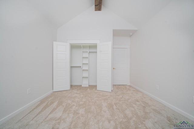 unfurnished bedroom with lofted ceiling with beams, light carpet, and a closet