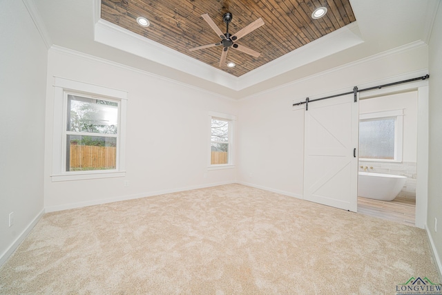 empty room featuring wood ceiling, light colored carpet, a raised ceiling, and a barn door