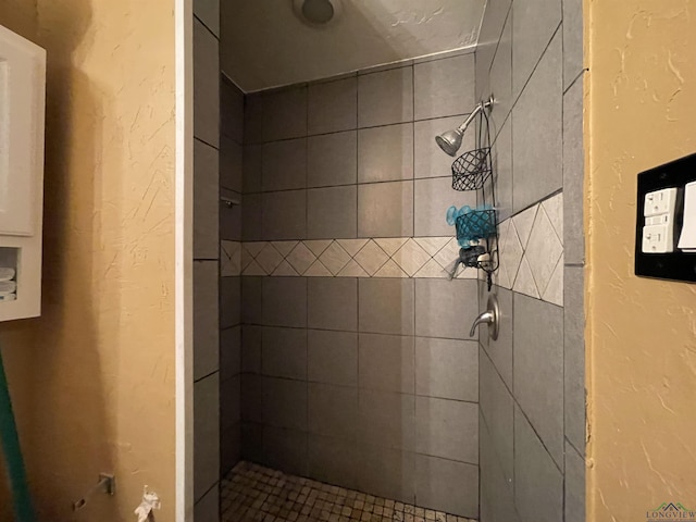 full bath with a tile shower and a textured wall
