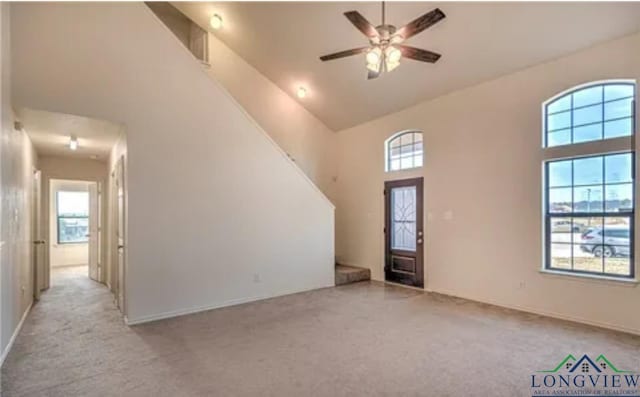 interior space with light colored carpet, a wealth of natural light, and a high ceiling