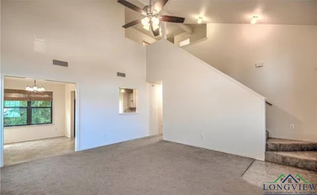 unfurnished living room featuring ceiling fan with notable chandelier, high vaulted ceiling, and carpet