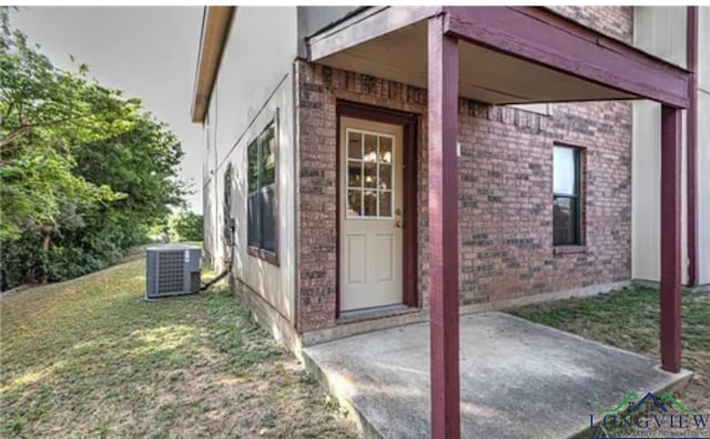 doorway to property with cooling unit, a lawn, and a patio